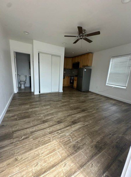 A room with a ceiling fan and wooden flooring.